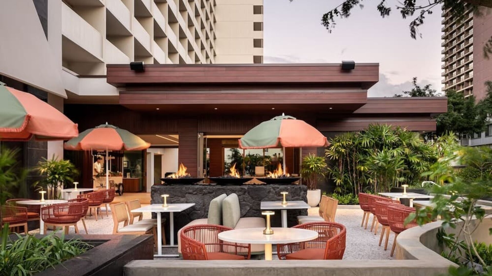 Outdoor patio area with seating, fire features, and landscaped surroundings at The Ambassador Hotel Of Waikiki.