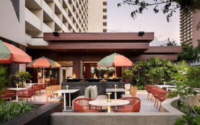 Outdoor patio area with seating, fire features, and landscaped surroundings at The Ambassador Hotel Of Waikiki.