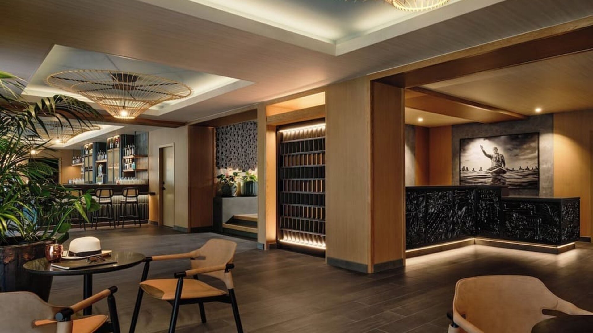 Reception lounge with warm lighting, wooden finishes, seating areas, and decorative ceiling fixtures at Romer House Waikiki