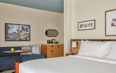 Blue sofa, round table, wooden cabinet, and wall art in a relaxed guest room at Romer House Waikiki.