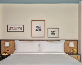 King bed centered in room with bedside tables, framed artwork, and neutral tones creating a calm space at Romer House Waikiki.