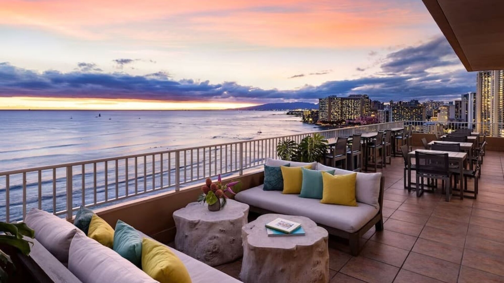 Sunset terrace with lounge seating overlooking ocean and Waikiki skyline at The Twin Fin Hotel.