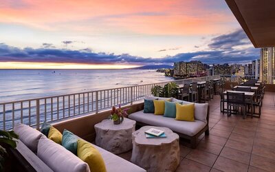 Sunset terrace with lounge seating overlooking ocean and Waikiki skyline at The Twin Fin Hotel.