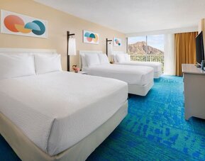 Room with three double beds, balcony view, and mountain backdrop at The Twin Fin Hotel.