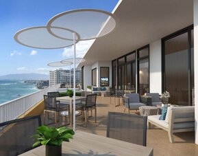 Large terrace with dining tables, lounge seating, and panoramic oceanfront views at The Twin Fin Hotel.