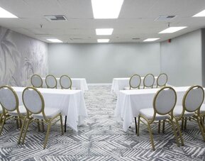 Meeting room with round-backed chairs, white tablecloths, and patterned carpet at The Twin Fin Hotel.
