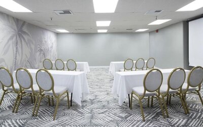 Meeting room with round-backed chairs, white tablecloths, and patterned carpet at The Twin Fin Hotel.