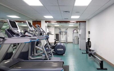 Gym with treadmills, rowing machine, and strength equipment in mirrored fitness room at The Twin Fin Hotel.