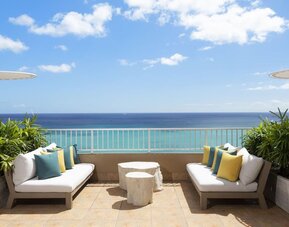 Outdoor seating area with ocean view, cushioned sofas, and umbrellas at The Twin Fin Hotel.