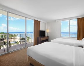 Room with two double beds, large windows, balcony, and ocean views at Park Shore Waikiki.