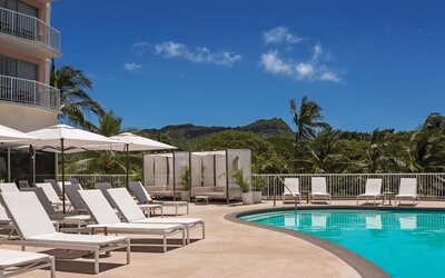 Pool deck with sun loungers, umbrellas, and mountain backdrop at Park Shore Waikiki.