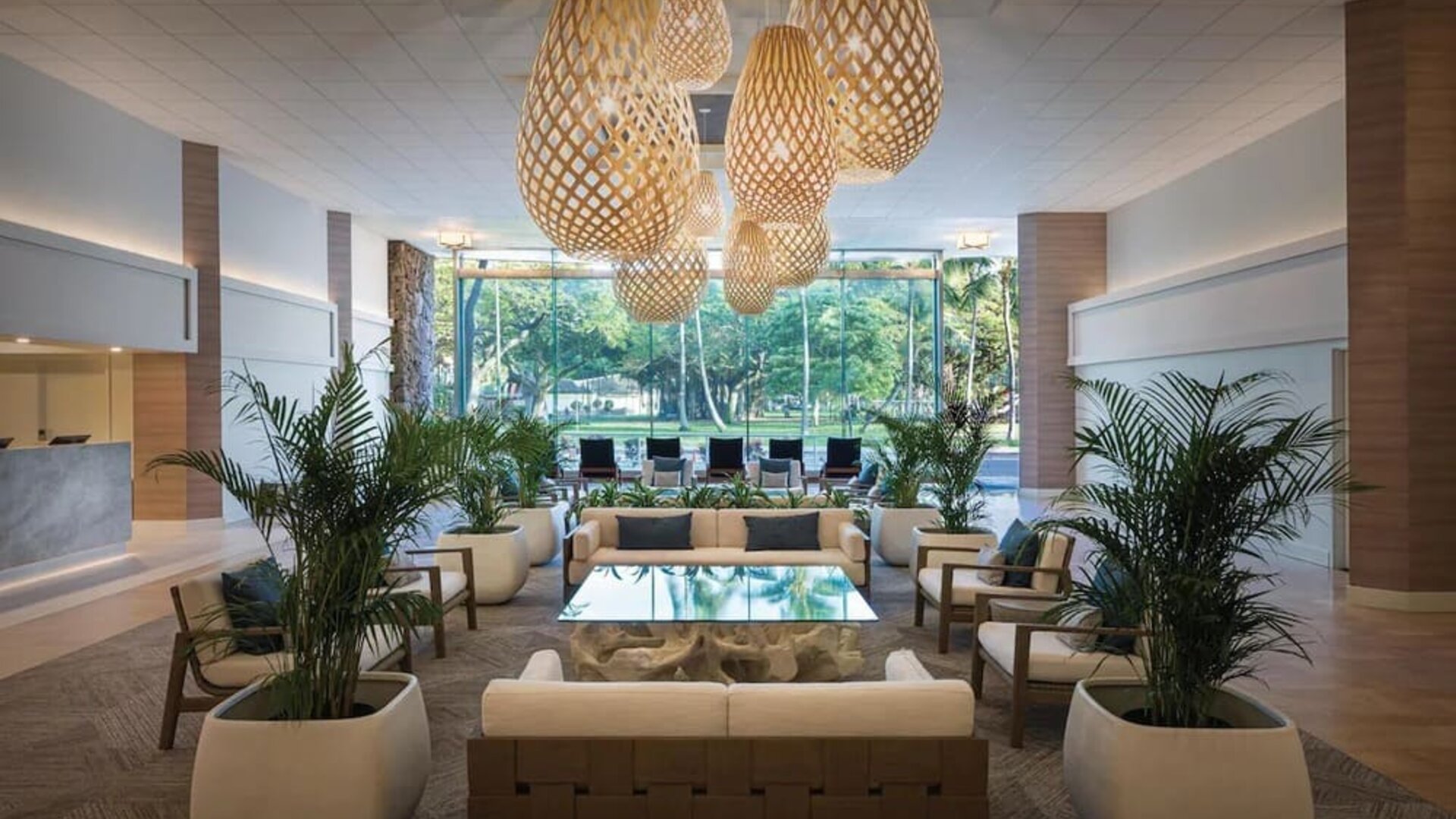 Spacious lobby with woven pendant lights, lounge seating, and large windows overlooking greenery at Park Shore Waikiki.