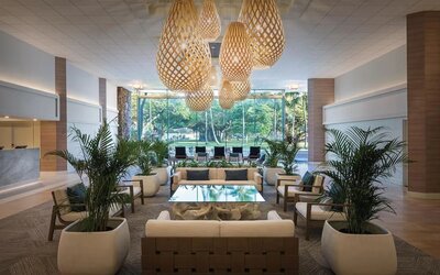 Spacious lobby with woven pendant lights, lounge seating, and large windows overlooking greenery at Park Shore Waikiki.