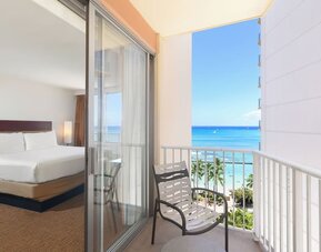 Room with king bed and sliding glass doors leading to a balcony with ocean and pool views at Park Shore Waikiki