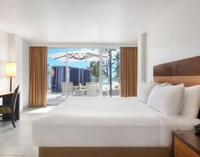 King bed room with desk, TV, and sliding doors opening to a patio with seating at Park Shore Waikiki.