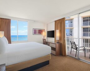 King bed room with balcony view of neighboring buildings and partial ocean view at Park Shore Waikiki.