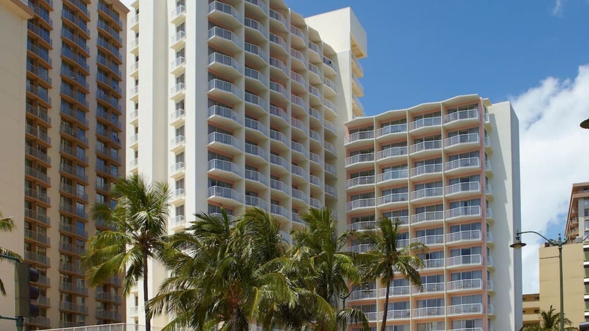 Exterior view of Park Shore Waikiki hotel building with balconies and palm trees in front.