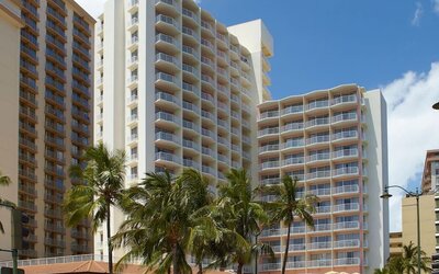 Exterior view of Park Shore Waikiki hotel building with balconies and palm trees in front.