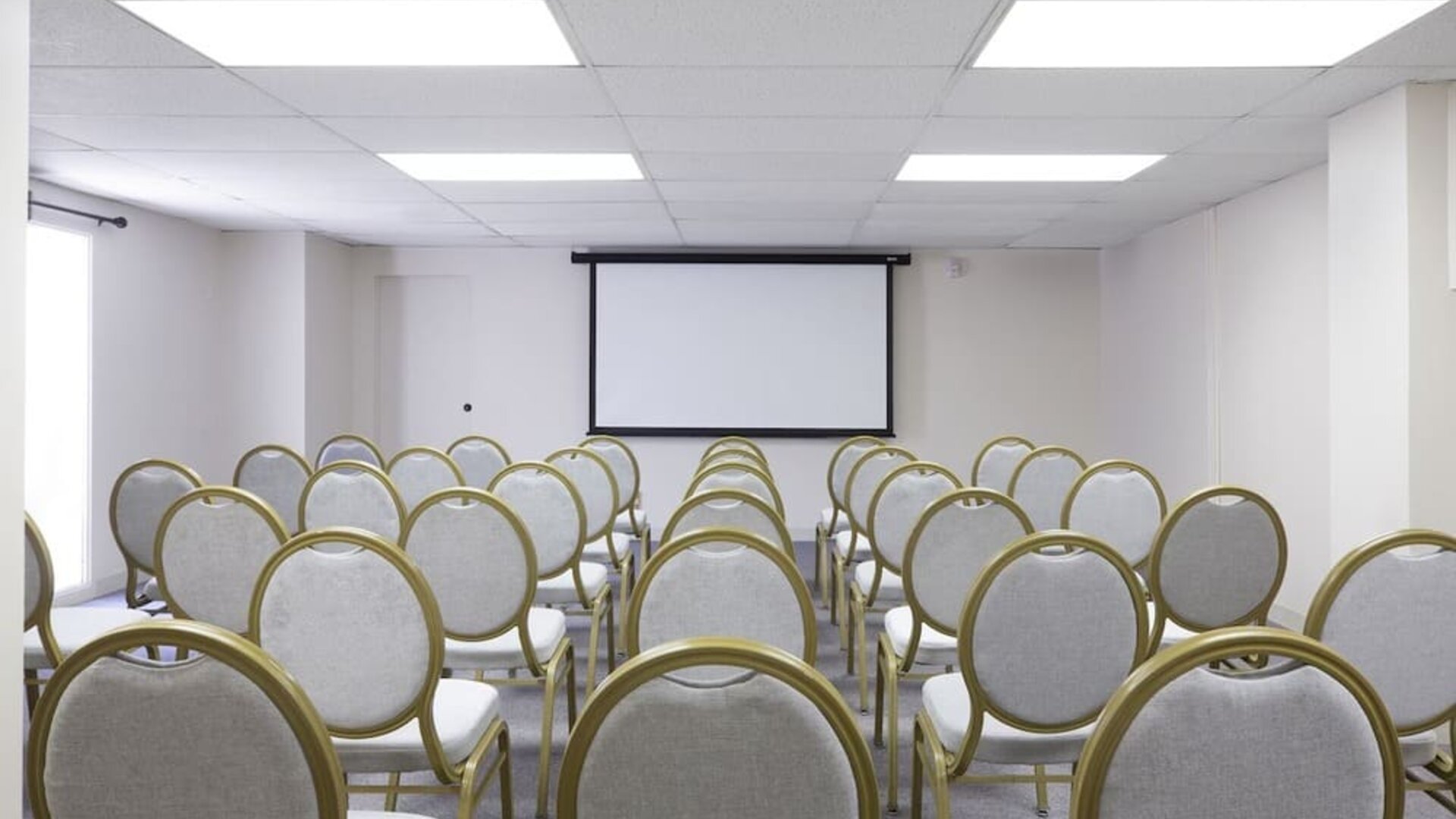 Meeting room with rows of chairs facing a presentation screen at Park Shore Waikiki.