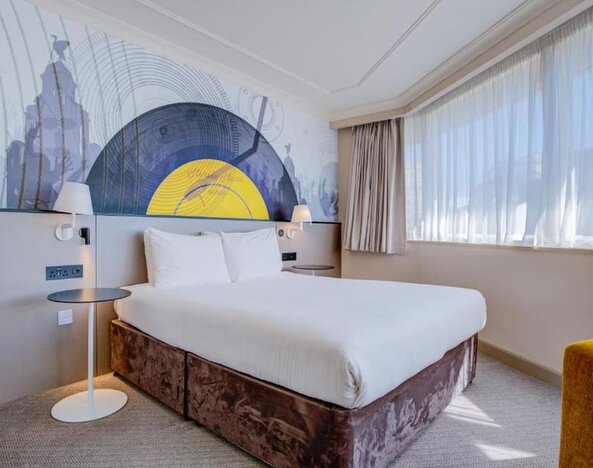 Bright double room with large bed, abstract mural headboard, and natural light from wide windows at Atlantic Tower Hotel Liverpool By Sunday.