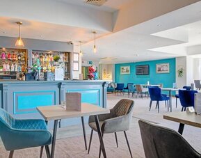 Stylish dining and bar area with blue accents, upholstered chairs, and pendant lighting at Atlantic Tower Hotel Liverpool By Sunday.