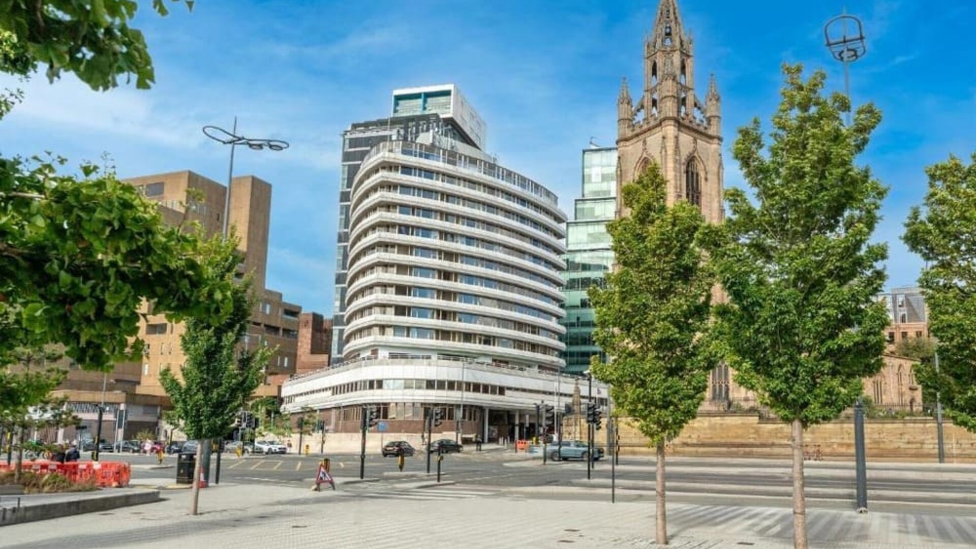 Exterior view of hotel building near historic church and city street at Atlantic Tower Hotel Liverpool By Sunday.