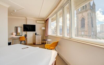 Guest room with large windows offering city views, workspace, and seating area at Atlantic Tower Hotel Liverpool By Sunday.