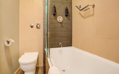 Modern bathroom with bathtub and overhead shower, neutral tiles, and wall-mounted toiletries at Atlantic Tower Hotel Liverpool By Sunday.