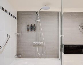 Bathroom with bathtub, rainfall shower, glass screen, and modern fixtures at Atlantic Tower Hotel Liverpool By Sunday.
