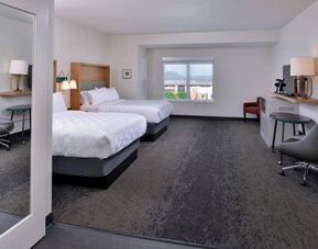 Double queen room with two beds, seating area, desk, and large window at Holiday Inn & Suites Farmington Hills - Detroit NW By IHG.