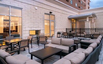 Outdoor seating area with cushioned sofas, tables, and covered entrance at Holiday Inn & Suites Farmington Hills - Detroit NW By IHG.