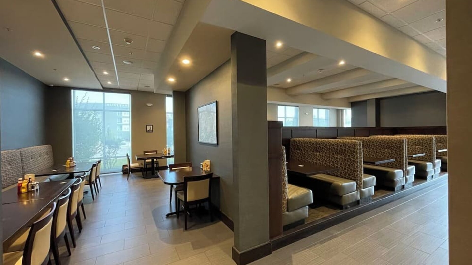 Dining area with booth seating, tables, and warm lighting at Holiday Inn & Suites Farmington Hills - Detroit NW By IHG.