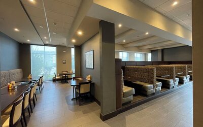 Dining area with booth seating, tables, and warm lighting at Holiday Inn & Suites Farmington Hills - Detroit NW By IHG.