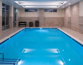 Indoor swimming pool with steps, tiled walls, and ceiling lights at Holiday Inn & Suites Farmington Hills - Detroit NW By IHG.
