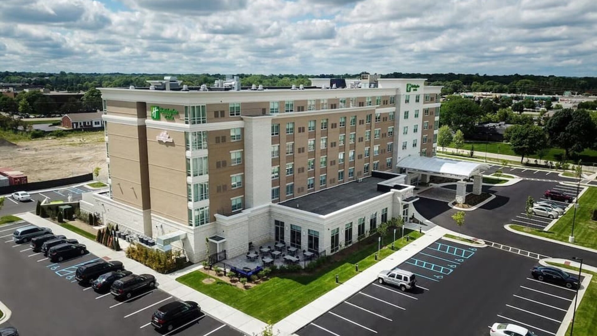 Aerial exterior view with parking lot, landscaped grounds, and hotel building at Holiday Inn & Suites Farmington Hills - Detroit NW By IHG.