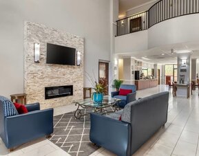 Lobby seating area with armchairs, coffee table, fireplace wall, and open layout at Comfort Suites Bush Intercontinental Airport.