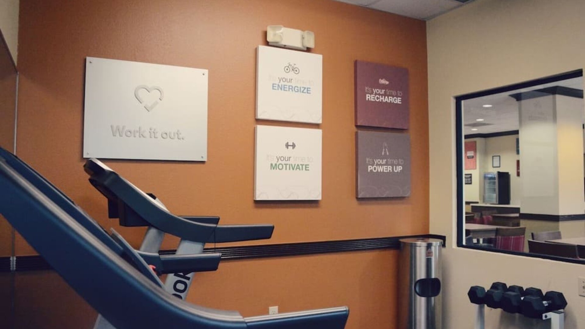 Fitness room with treadmill, dumbbells, wall mirror, and motivational wall signs at Comfort Suites Bush Intercontinental Airport
