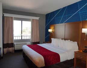 Day room with accent wall, bedside lighting, and window with curtains and air conditioning unit at Comfort Suites Bush Intercontinental Airport.