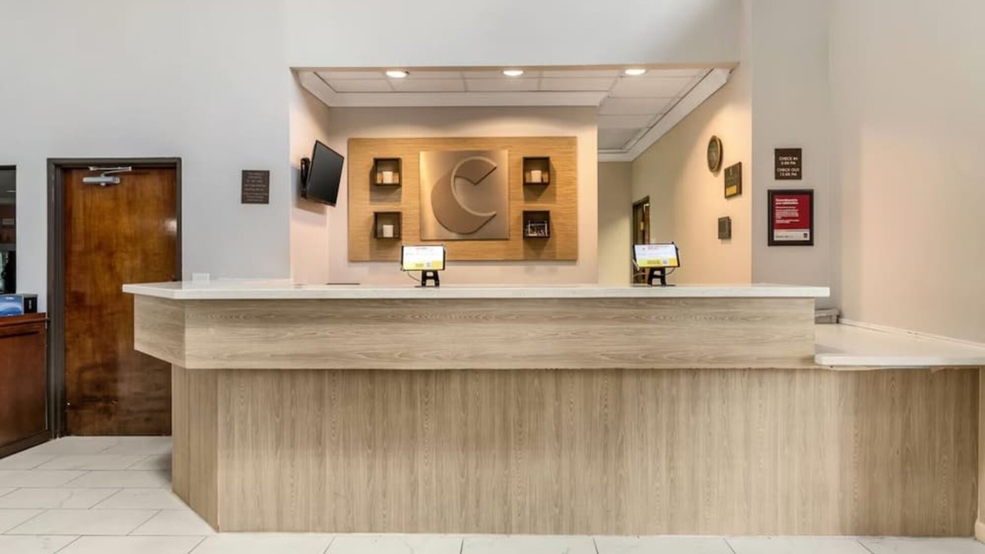 Reception desk with light wood finish, wall decor, and check-in computers at Comfort Suites Bush Intercontinental Airport.