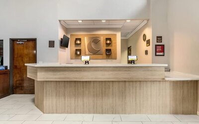 Reception desk with light wood finish, wall decor, and check-in computers at Comfort Suites Bush Intercontinental Airport.