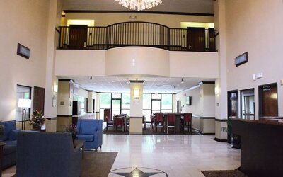 Lobby with high ceiling, chandelier, seating area, and reception desk in an open space at Comfort Suites Bush Intercontinental Airport.