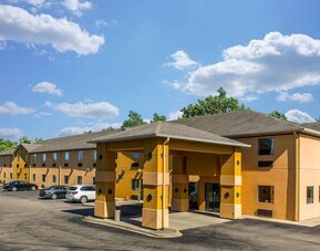 Exterior view of hotel building with covered entrance, parking area, and surrounding greenery at Suburban Studios Mason Hwy-42.