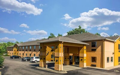Exterior view of hotel building with covered entrance, parking area, and surrounding greenery at Suburban Studios Mason Hwy-42.