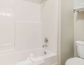 Bathroom with bathtub shower combo, toilet, and folded towels on rack at Suburban Studios Mason Hwy-42.