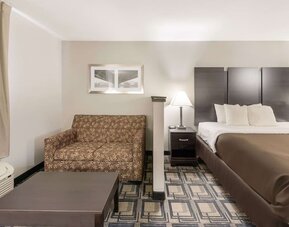 King room with sofa seating, coffee table, bedside lamps, and window with curtains at Suburban Studios Mason Hwy-42.