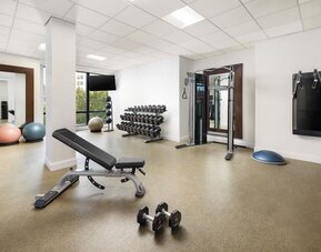 Gym area with strength equipment, dumbbells, and open workout space at M Social New York Downtown.
