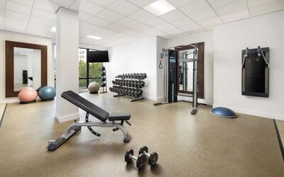 Gym area with strength equipment, dumbbells, and open workout space at M Social New York Downtown.