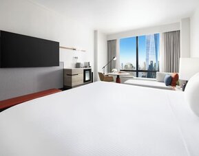 King room with large bed, wall-mounted TV, workspace, and floor-to-ceiling window with city view at M Social New York Downtown.