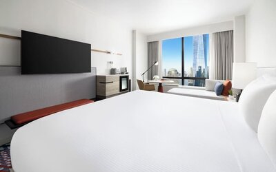 King room with large bed, wall-mounted TV, workspace, and floor-to-ceiling window with city view at M Social New York Downtown.