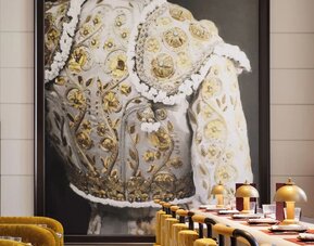Restaurant interior with bar seating, gold upholstered chairs, marble tables, and large statement artwork at M Social New York Downtown.